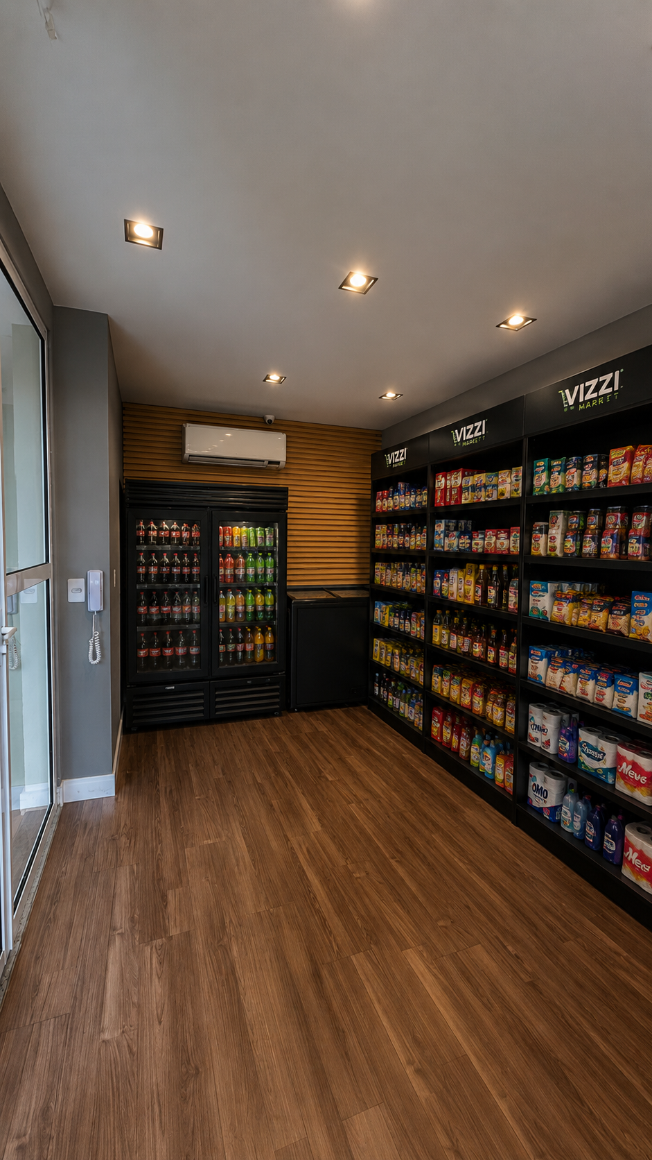 Vista ampla do Vizzi Market instalado em condomínio: geladeira de bebidas e parede de prateleiras